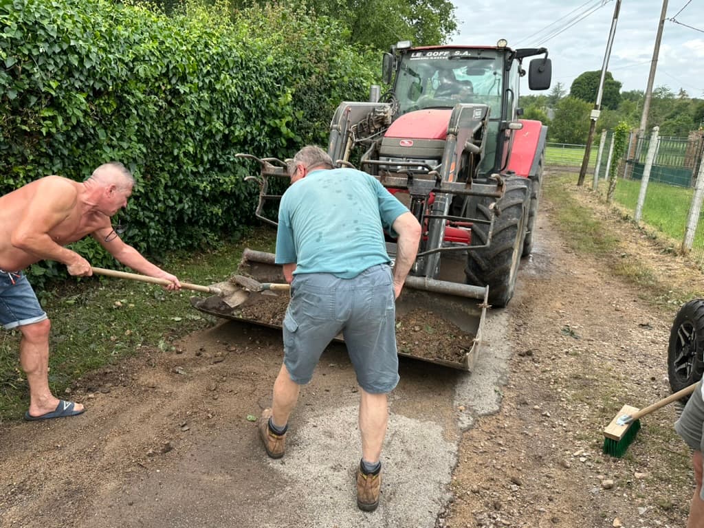 Les habitants du Voisinet et des membres du conseil municipal en train de nettoyer la route après un violent orage.