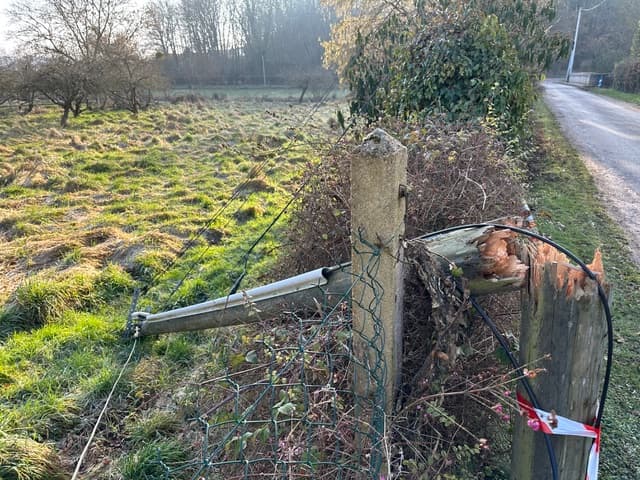 Poteau télécom en bois avec des câbles électriques et des antennes de télécommunications. Le poteau est cassé en deux parties et est posé sur le sol.